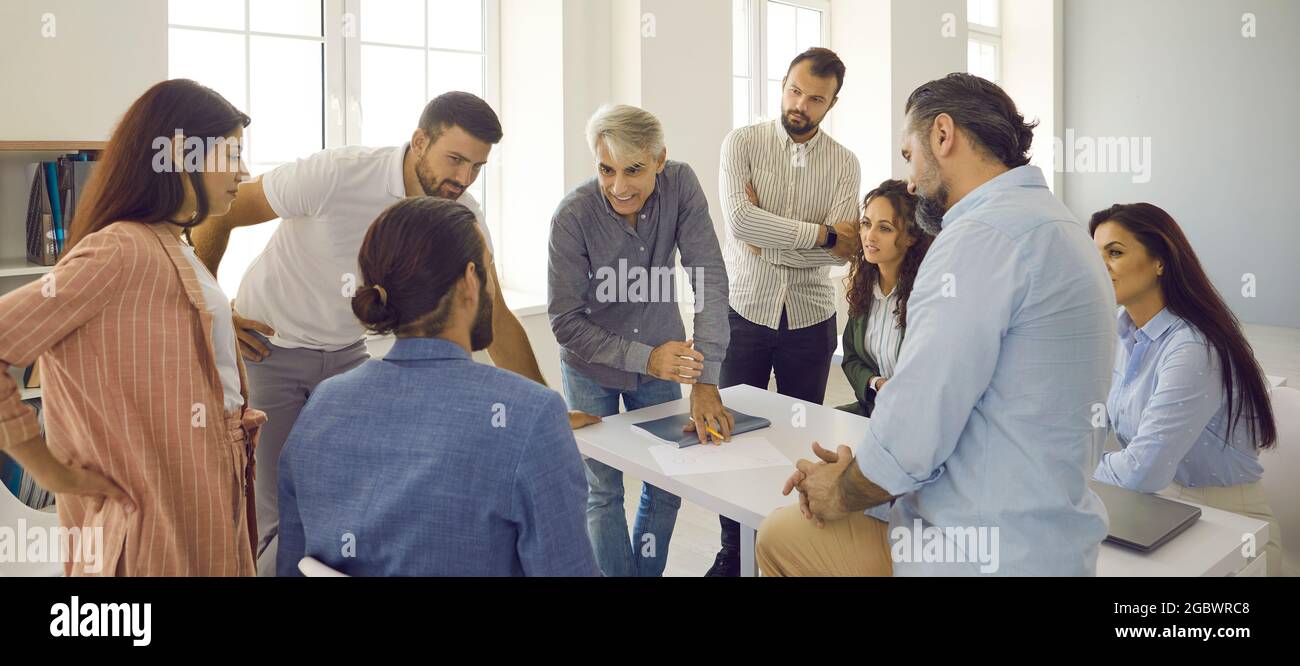 Gruppo di persone che si incontrano in ufficio e che hanno una discussione con un insegnante di affari senior Foto Stock