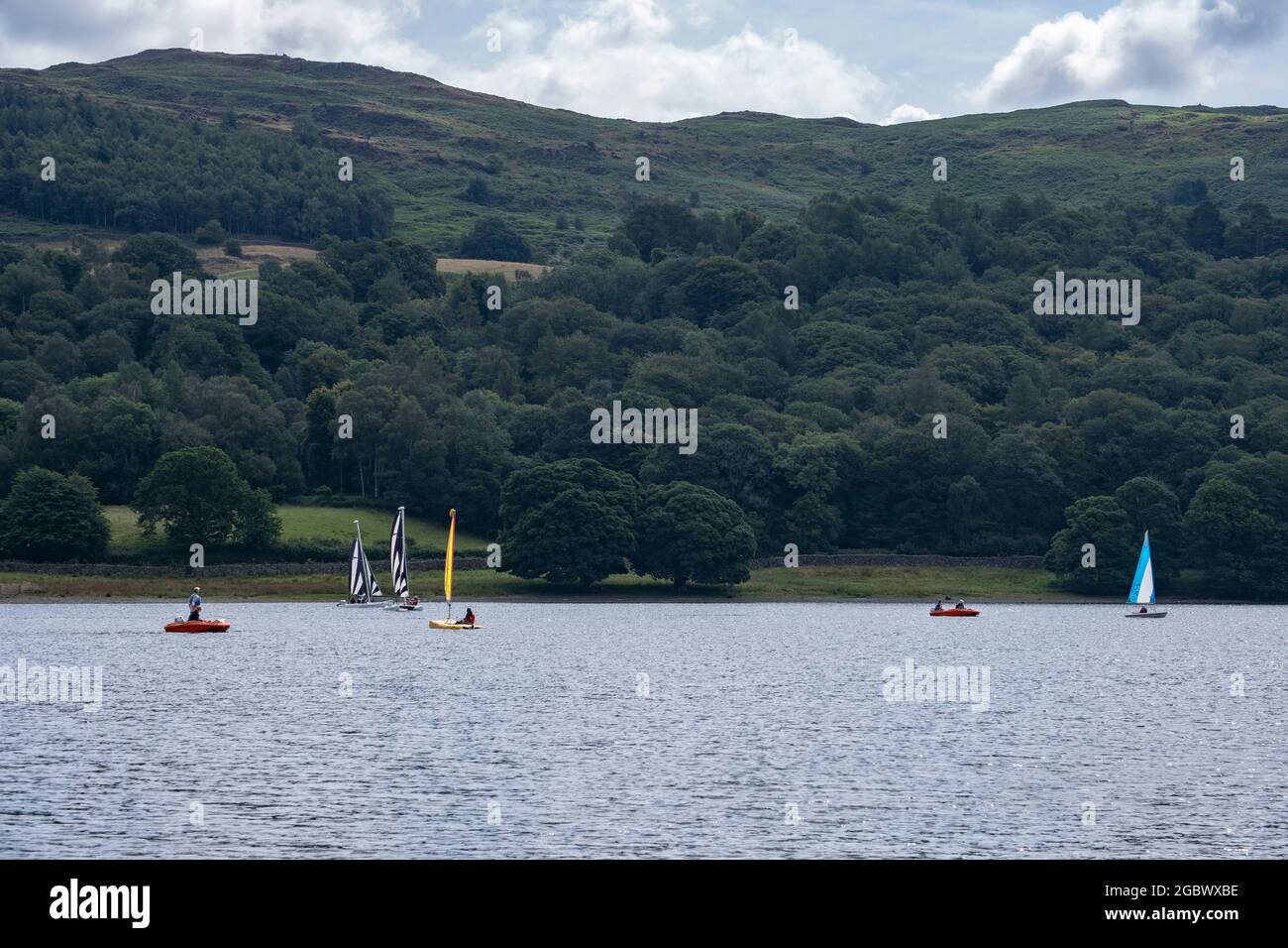 Tavole da paddle, canoe e nuotatori approfittano delle ottime condizioni per godersi l'acqua di Coniston nel Lake District, Inghilterra. Foto Stock