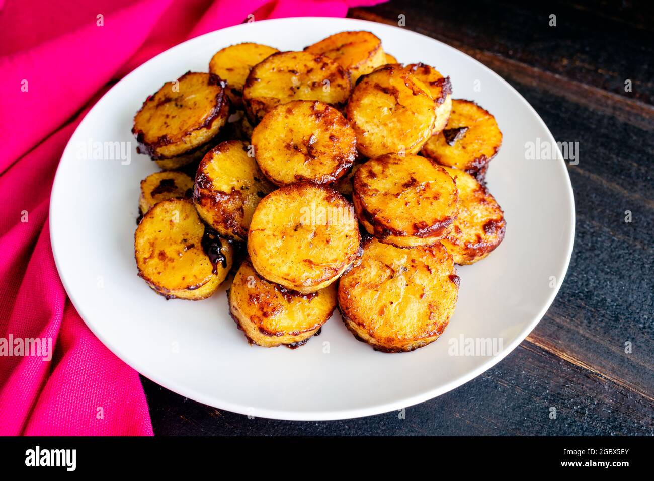 Piantane dolci cotte alla cannella al caramello: Un piatto di piantine cotte al forno ricoperte di cannella e zucchero caramellato Foto Stock