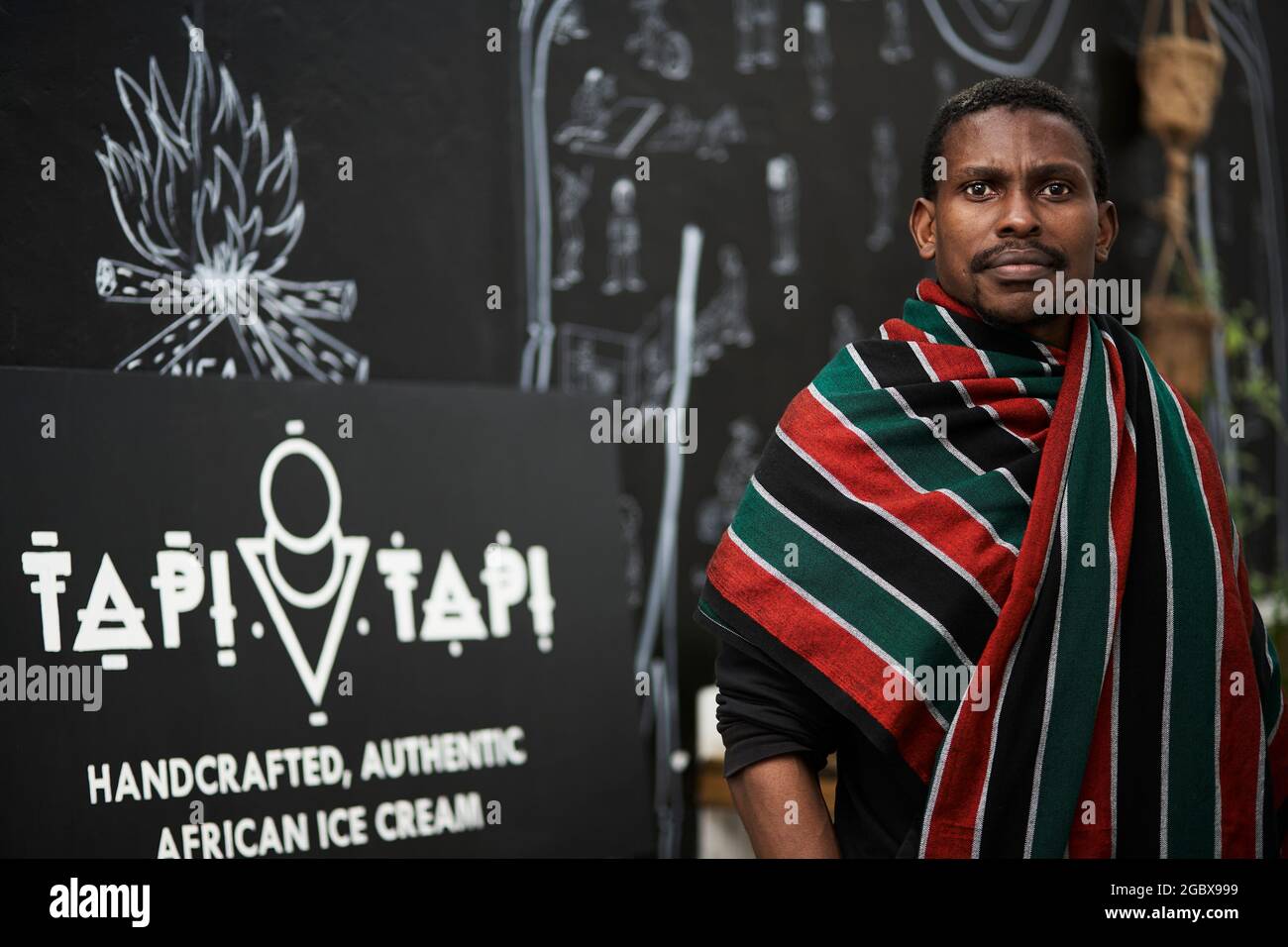 Il proprietario di affari sudafricano, Tapiwa Guzha, nella sua gelateria chiamata TAPI TAPI. TAPI TAPI è un ideofono bantu che significa dolce. Foto Stock