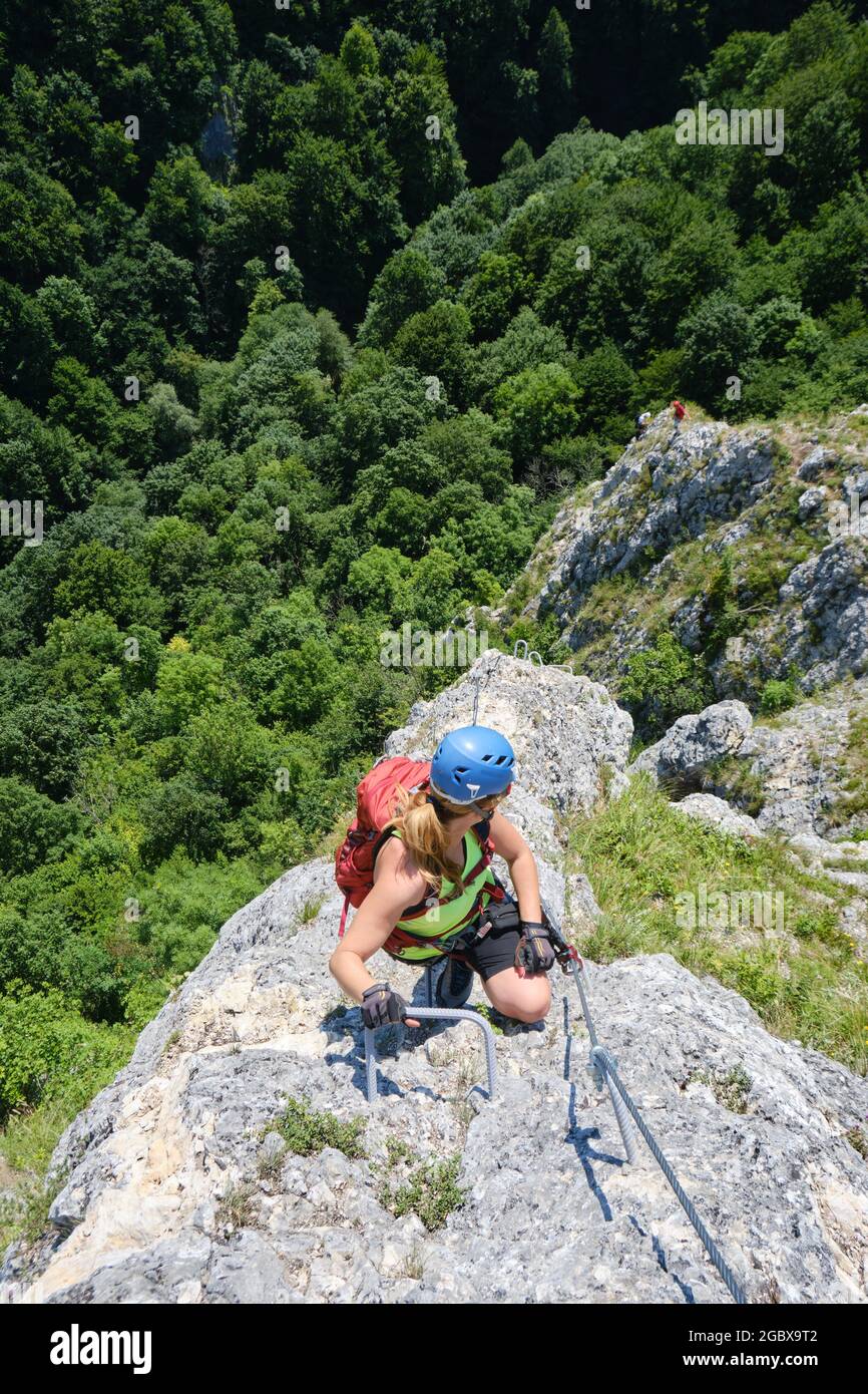 Donna guarda giù sulla via ferrata chiamata Soim Calator, sopra le gole di Varghis, i monti Persani, Romania. Attività estive, avventura, turismo a ha Foto Stock
