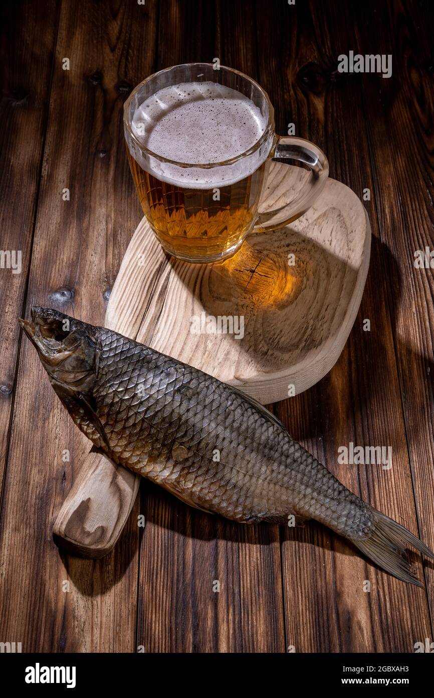 Birra con pesce secco e spuntini su tavola di legno. Foto Stock