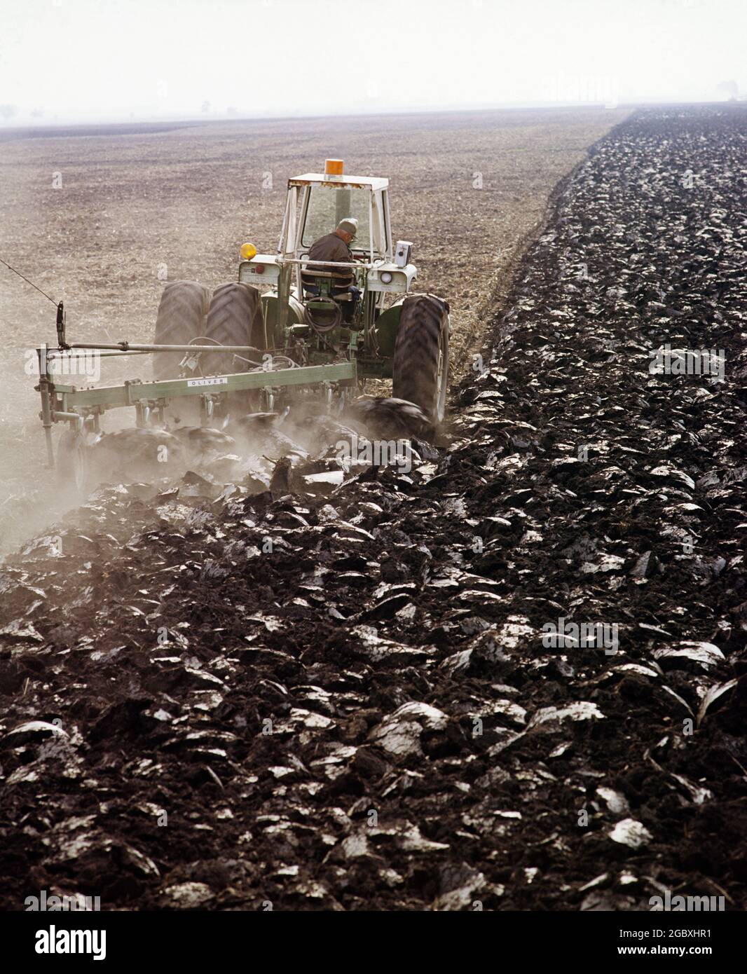 ANNI '80 UOMO CONTADINO ANONIMO DALLE SILHOUETTE SINGOLE CHE ARANO TERRENI UMIDI CON UN POTENTE TRATTORE CHE TIRA SEI ARATRI INFERIORI - KF12187 HEL001 HARS AGRICOLTURA MASCHI SEI PROFESSIONE SUOLO AGRICOLTURA SPORCO OBIETTIVI FINO ABILITÀ OCCUPAZIONE COMPETENZE TESTA E SPALLE MACCHINARI ARATRO SILHOUETTED CARRIERE AGRICOLTORI POTENTE LAVORO ARATURA ORGOGLIO OCCUPAZIONE OCCUPAZIONI CONCETTUALE TERRENI AGRICOLI ANONIMI CRESCITA DEI DIPENDENTI TERRENO MEDIO-ADULTO UOMO MEDIO-ADULTO ARATRO PRIMAVERA COLTIVARE LAVORO VECCHIO ALLA MODA Foto Stock