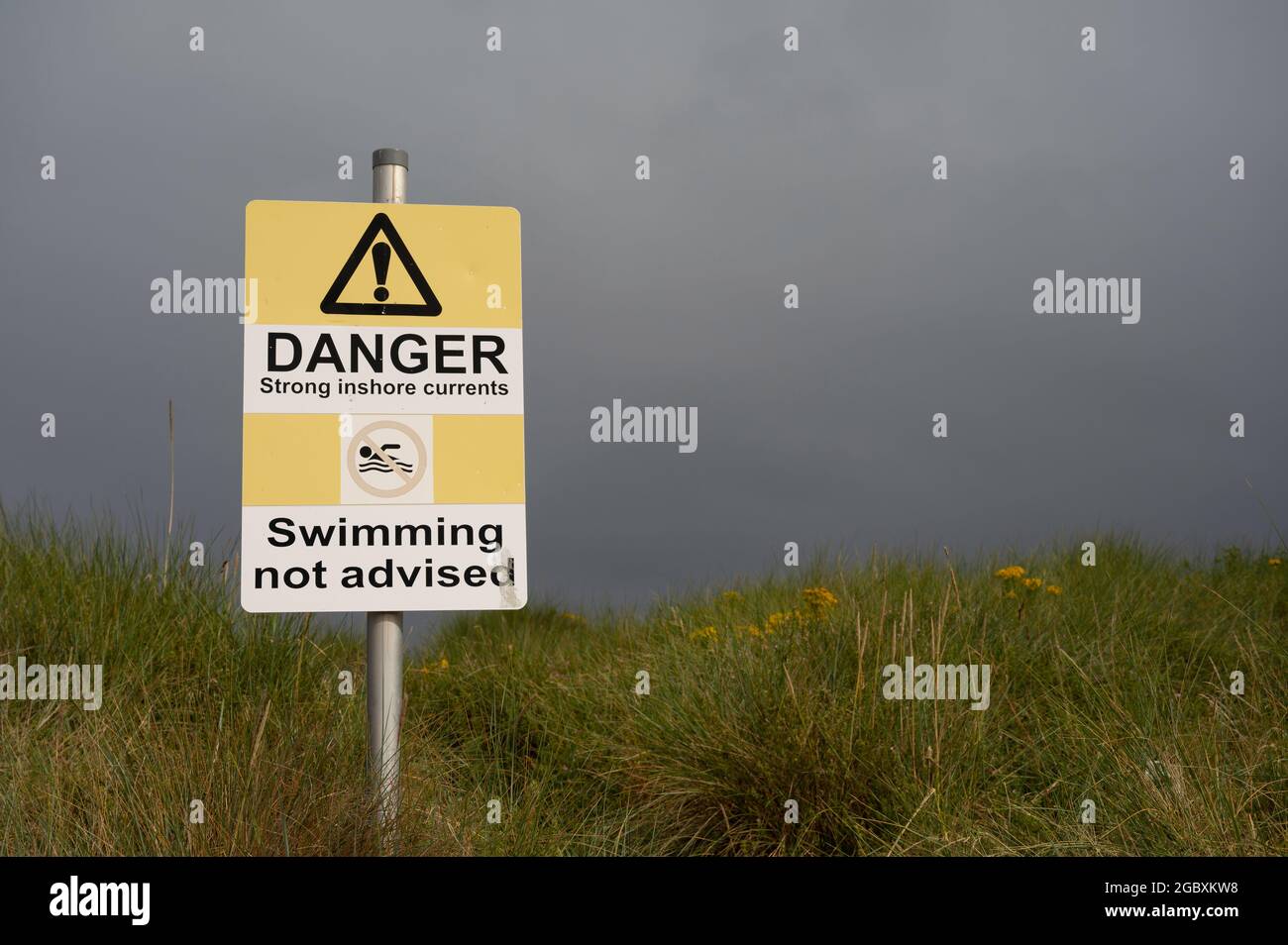 Pericolo forti correnti costiere nuoto non consigliato segno con icone. Autentico, sul sentiero della spiaggia. Nessuna gente. Foto Stock