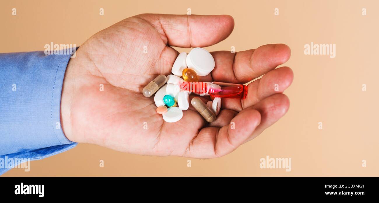 Medicina e trattamenti. Mano dell'uomo con pillole. Terapia farmacologica. Compresse prescritte dal medico. Foto Stock