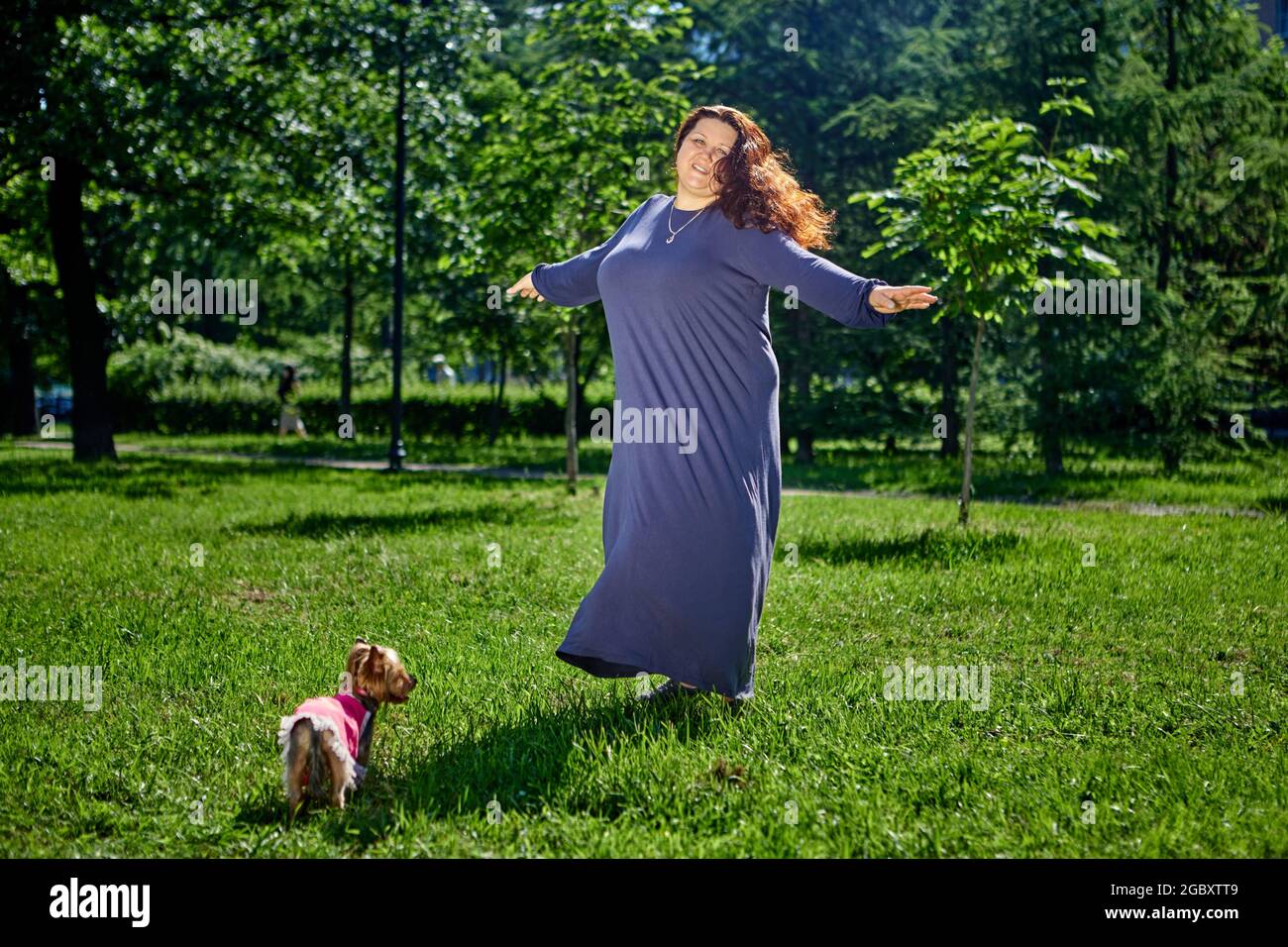 Più taglia donna che balla sul prato in lungo abito estivo. Foto Stock