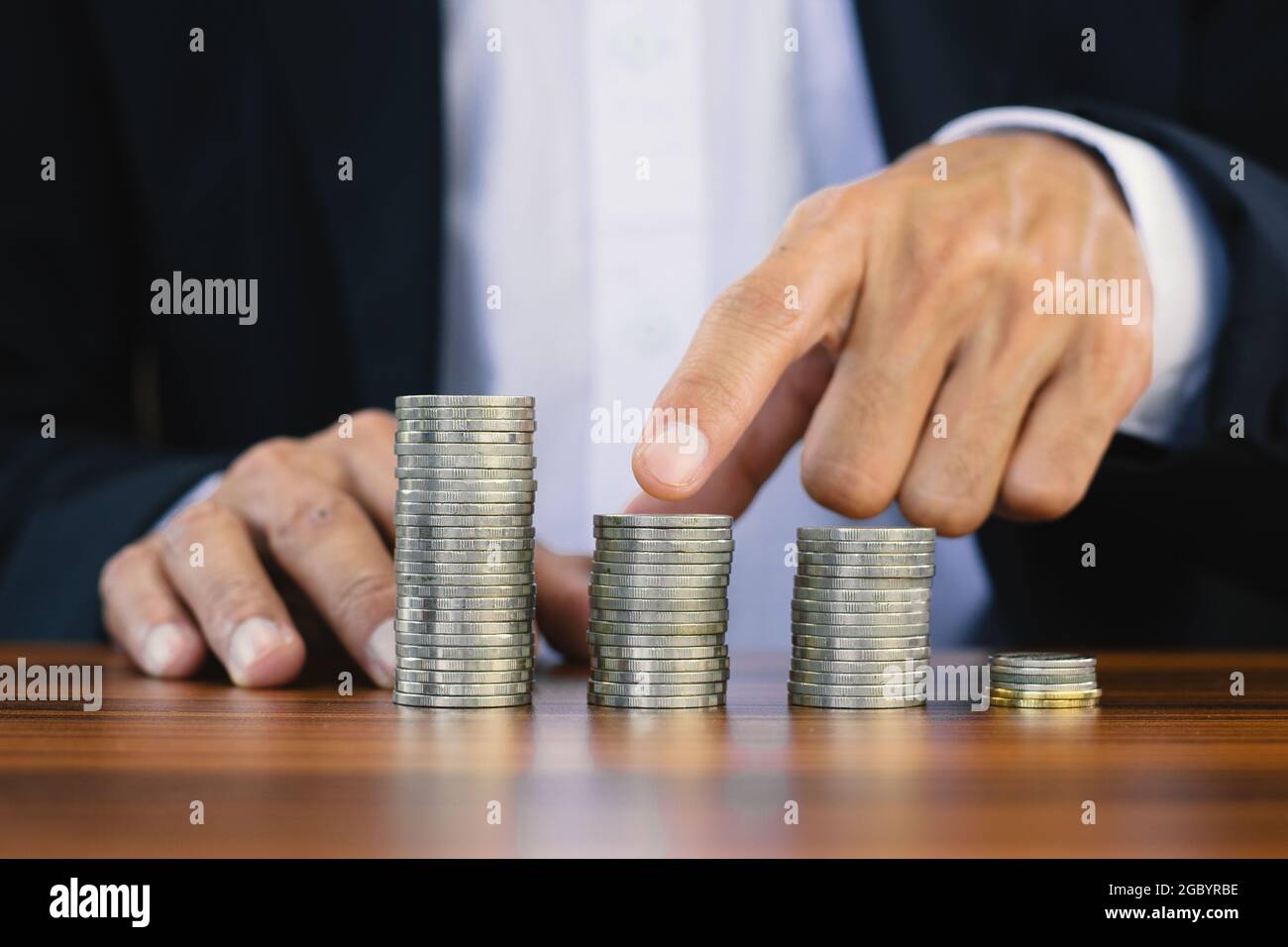 Contatto di uomo d'affari su pila di monete su tavola di legno, monete di impilamento dell'uomo per la pensione di soldi di risparmio, pila di monete degli uomini per l'investimento Foto Stock