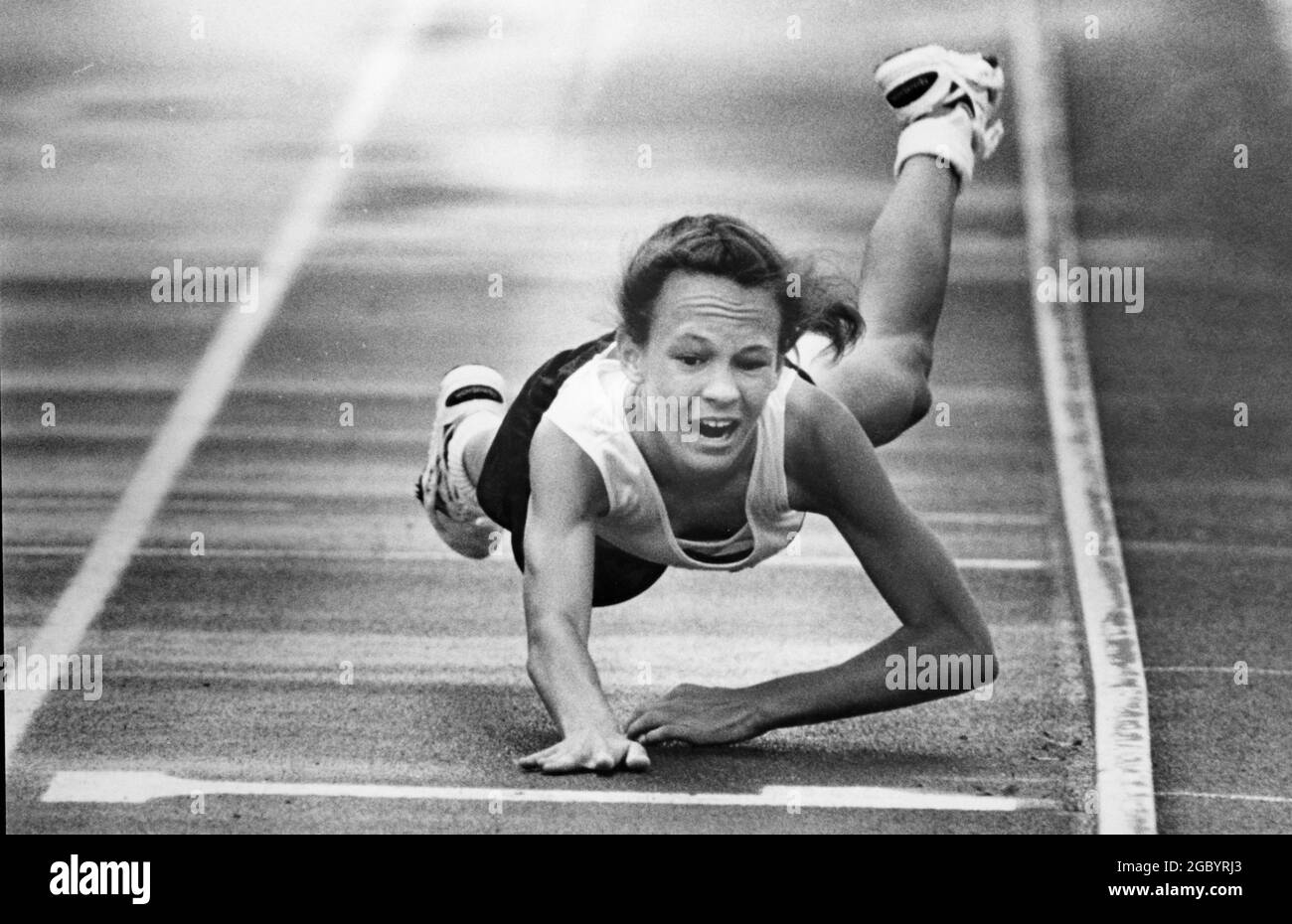 Austin Texas USA, circa 1992: Concorrente nelle ragazze 800 metri di corsa cade come lei si allunga per il traguardo alla pista di High School stato e campionato di campo si incontrano. ©Bob Daemmrich Foto Stock