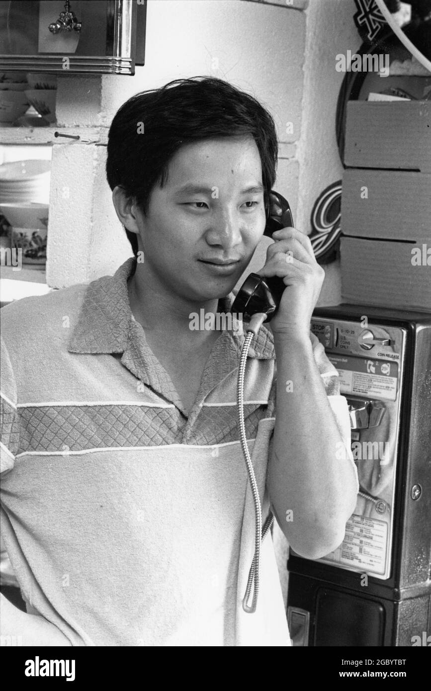 Austin Texas USA, 1993: Uomo asiatico-americano negoziante parla a sul telefono a pagamento nella sua attività. SIG. EP-0091 ©Bob Daemmrich Foto Stock