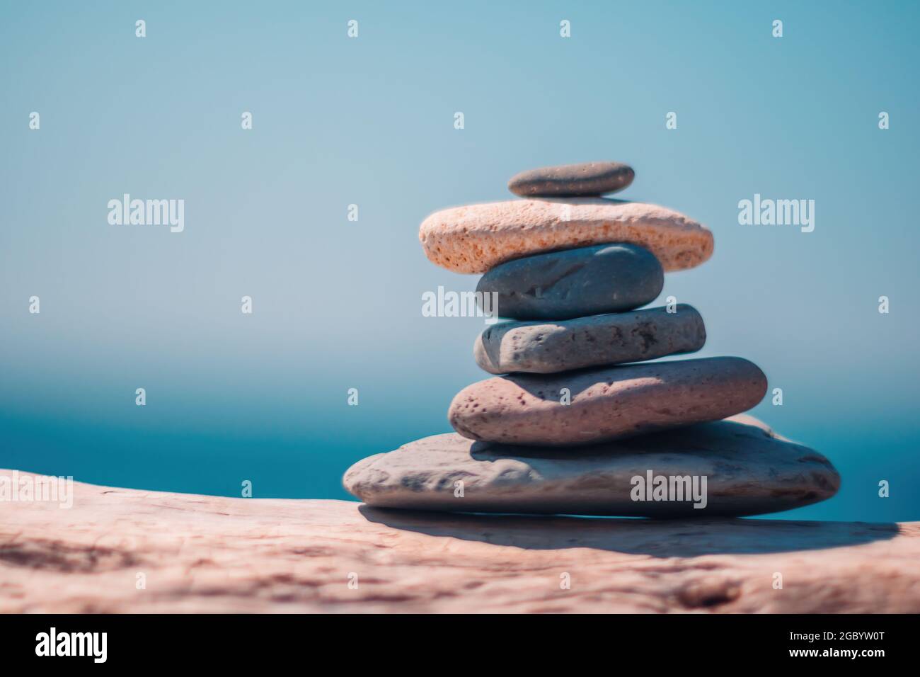 Equilibrata piramide di ciottoli sulla spiaggia in una giornata di sole. Abstract Sea bokeh sullo sfondo. Messa a fuoco selettiva. Pietre Zen sulla spiaggia di mare, meditazione Foto Stock