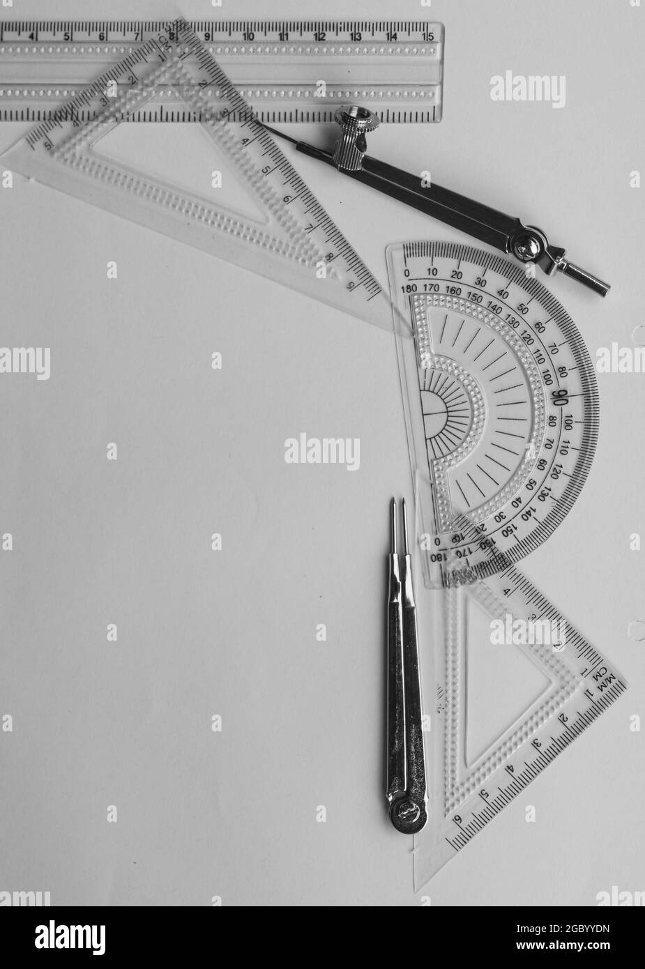 Strumenti di misurazione geometrica, elementi di disegno e strumenti matematici collocati su fogli di carta bianca. Ritorno a scuola e formazione tecnica b Foto Stock