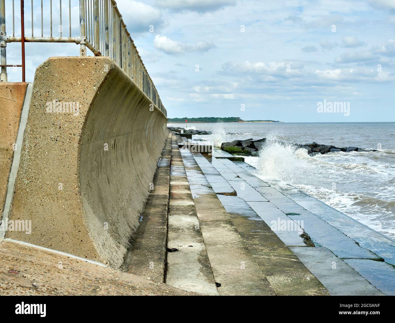 Parete del mare recurvata con base a gradini e barriera corrimano in alto. Foto Stock