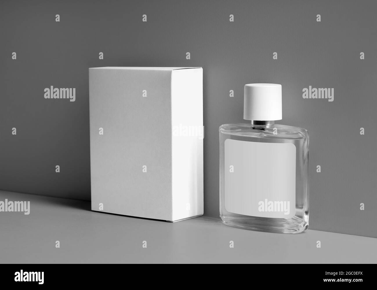 Modello di scatola di cartone bianca, bottiglia trasparente per profumo, con etichetta, tappo in plastica, su fondo grigio. Modello di confezionamento per Essence, Foto Stock