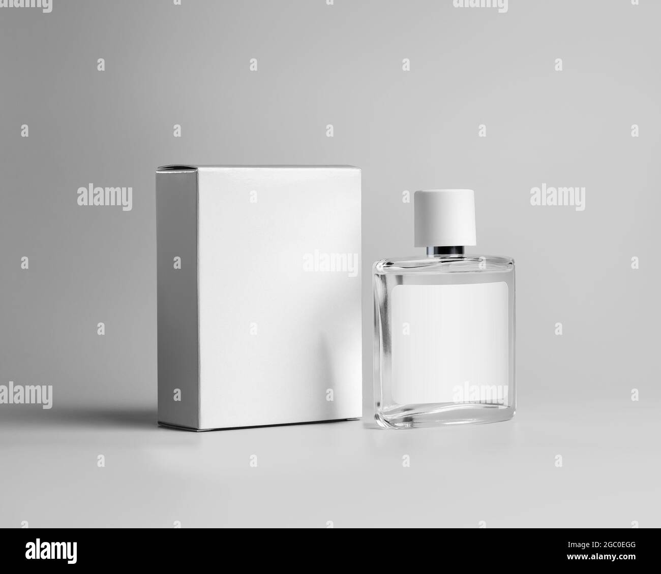Modello di una bottiglia di vetro trasparente per profumo, con etichetta per il disegno, una scatola di cartone bianca per un profumo di marca, fragranza. Pubblicità cosmetica Foto Stock
