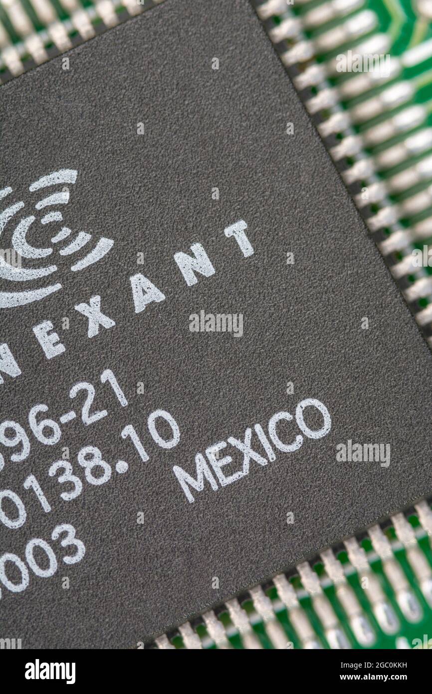 Macro primo piano di un microchip realizzato in Messico su una scheda modem legacy pcb con righe di piedini visibili. Chip realizzato da Conexant. Foto Stock