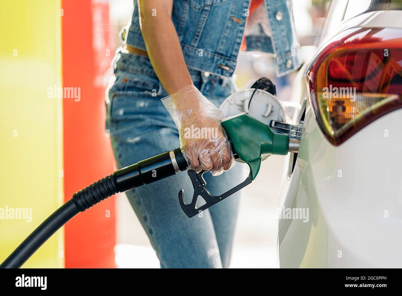 Donna africana non riconosciuta che indossa guanti di plastica riempiendo  la sua auto con benzina alla stazione di servizio Foto stock - Alamy