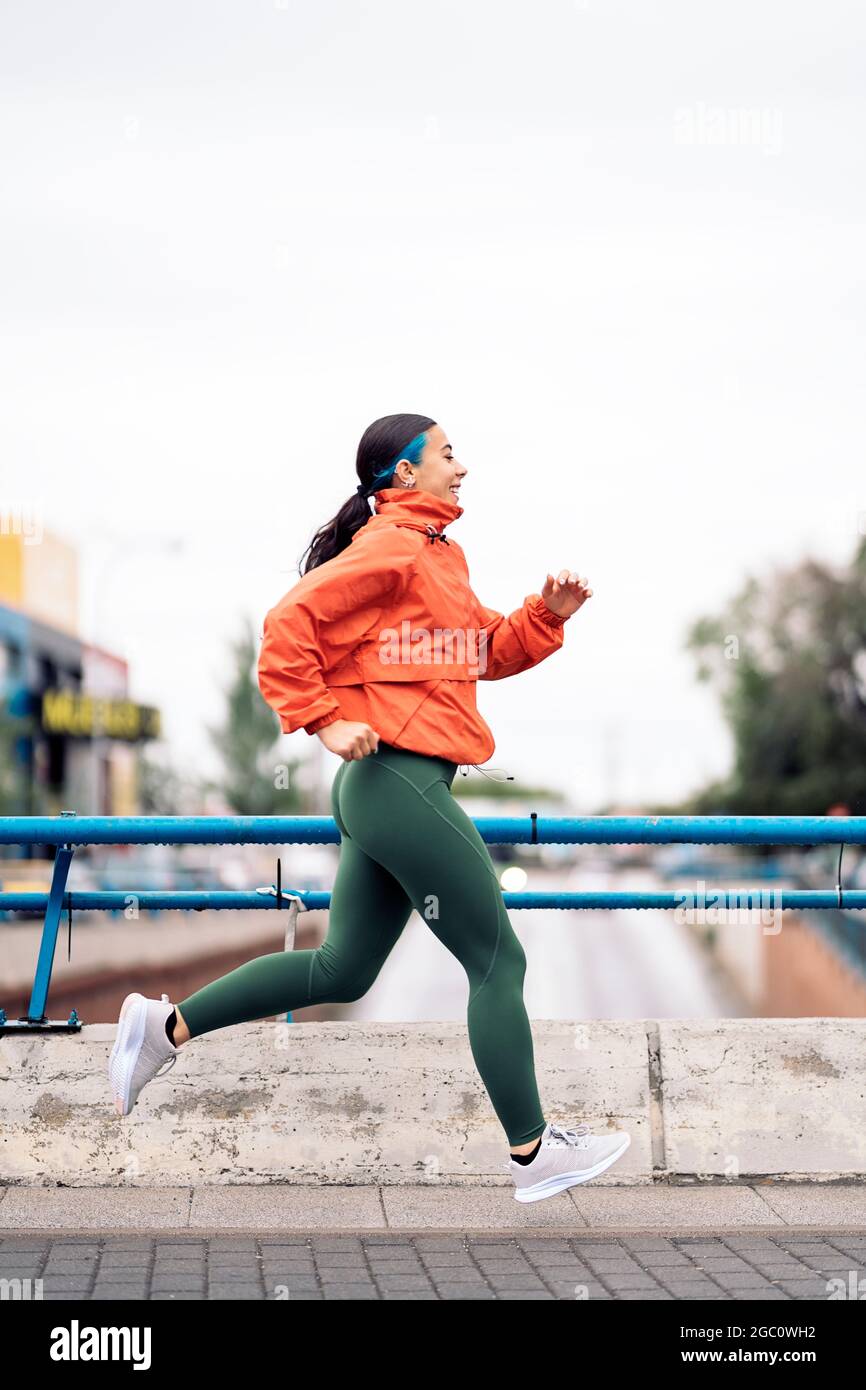 Bella ragazza che indossa abiti sportivi divertirsi in città mentre si allenano. Il tempo è piovoso. Foto Stock