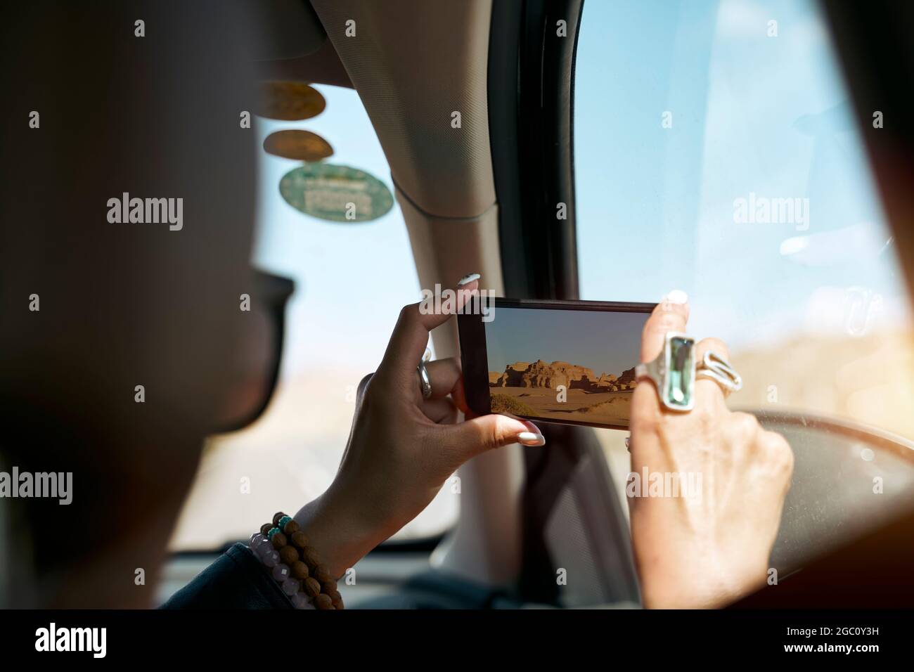 passeggero turistico asiatico femmina scattare una foto utilizzando il cellulare dall'interno di un'auto Foto Stock