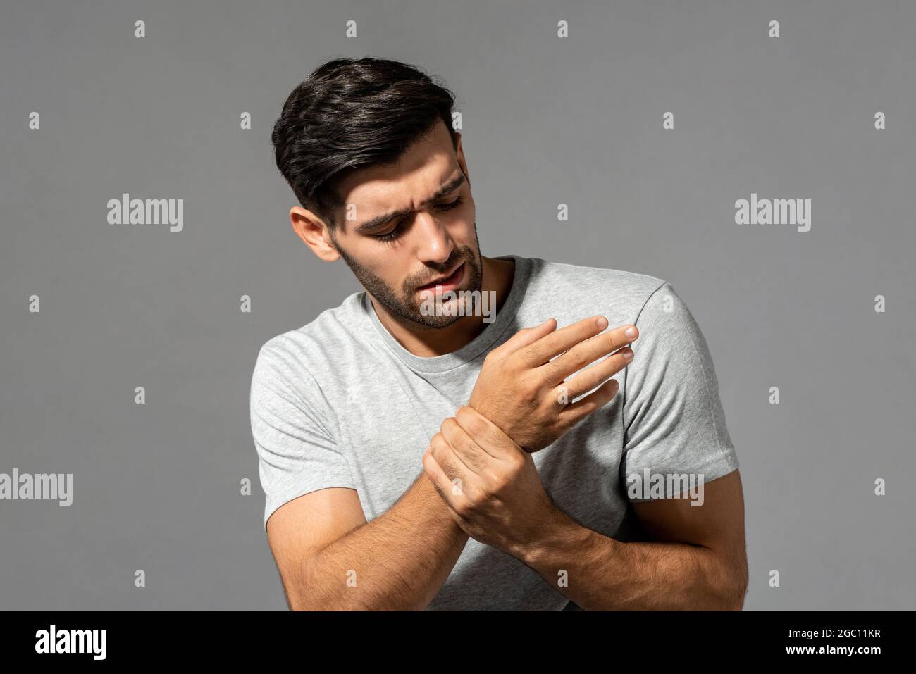 Giovane uomo caucasico che ha dolore al polso, studio girato su sfondo grigio isolato Foto Stock