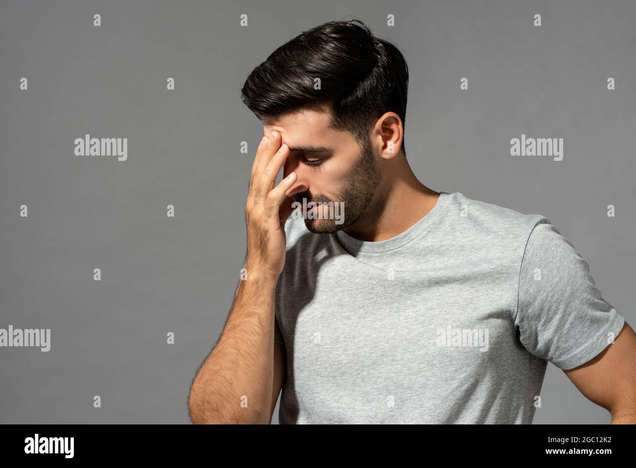 Giovane uomo caucasico che ha mal di testa e sforzo oculare, studio girato su sfondo grigio isolato Foto Stock