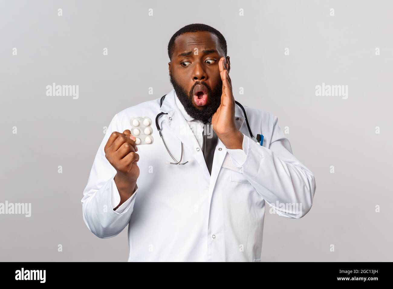 Influenza, malattia, assistenza sanitaria e medicina concetto. Preoccupato e imbarazzato medico afro-americano disposto mescolato-in su, dà il farmaco errato a. Foto Stock