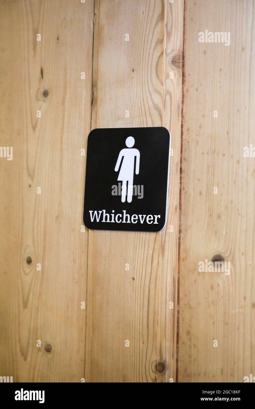 Un segno su una porta di gabinetto unisex che dice 'qualunque' con una foto, un pittogramma o simbolo di mezzo uomo e mezzo donna, Inghilterra, Regno Unito Foto Stock
