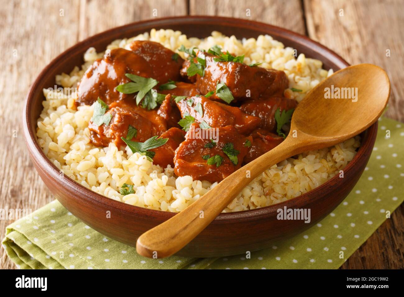 Maiale brasato lentamente in vino rosso servito con il bulgur primo piano in una ciotola sul tavolo. Orizzontale Foto Stock