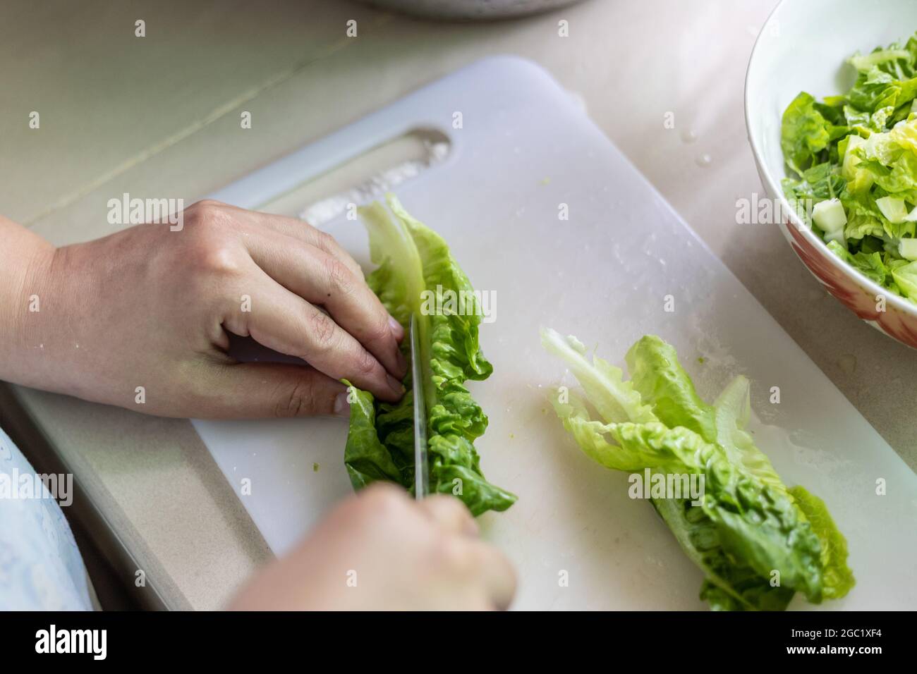 Stile di vita locale casalinga tagliare verdure preparandosi per cucinare Foto Stock