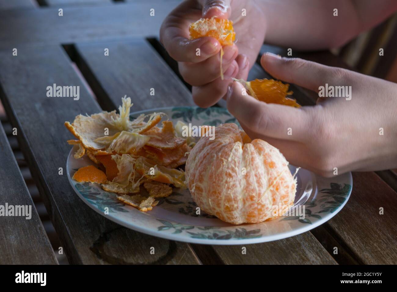 Colpo di closeup delle mani che spellano un mandarino. Foto Stock