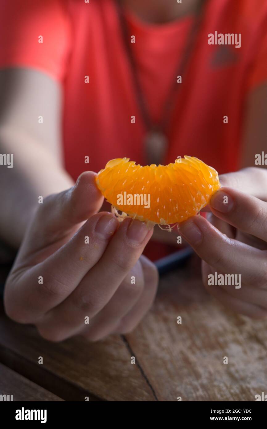 Colpo verticale di mani che tengono un tangerino pelato. Foto Stock