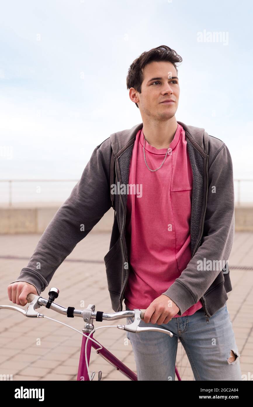 ritratto verticale di un bel giovane che cammina con una bici d'epoca, concetto di trasporto sostenibile e stile di vita urbano Foto Stock