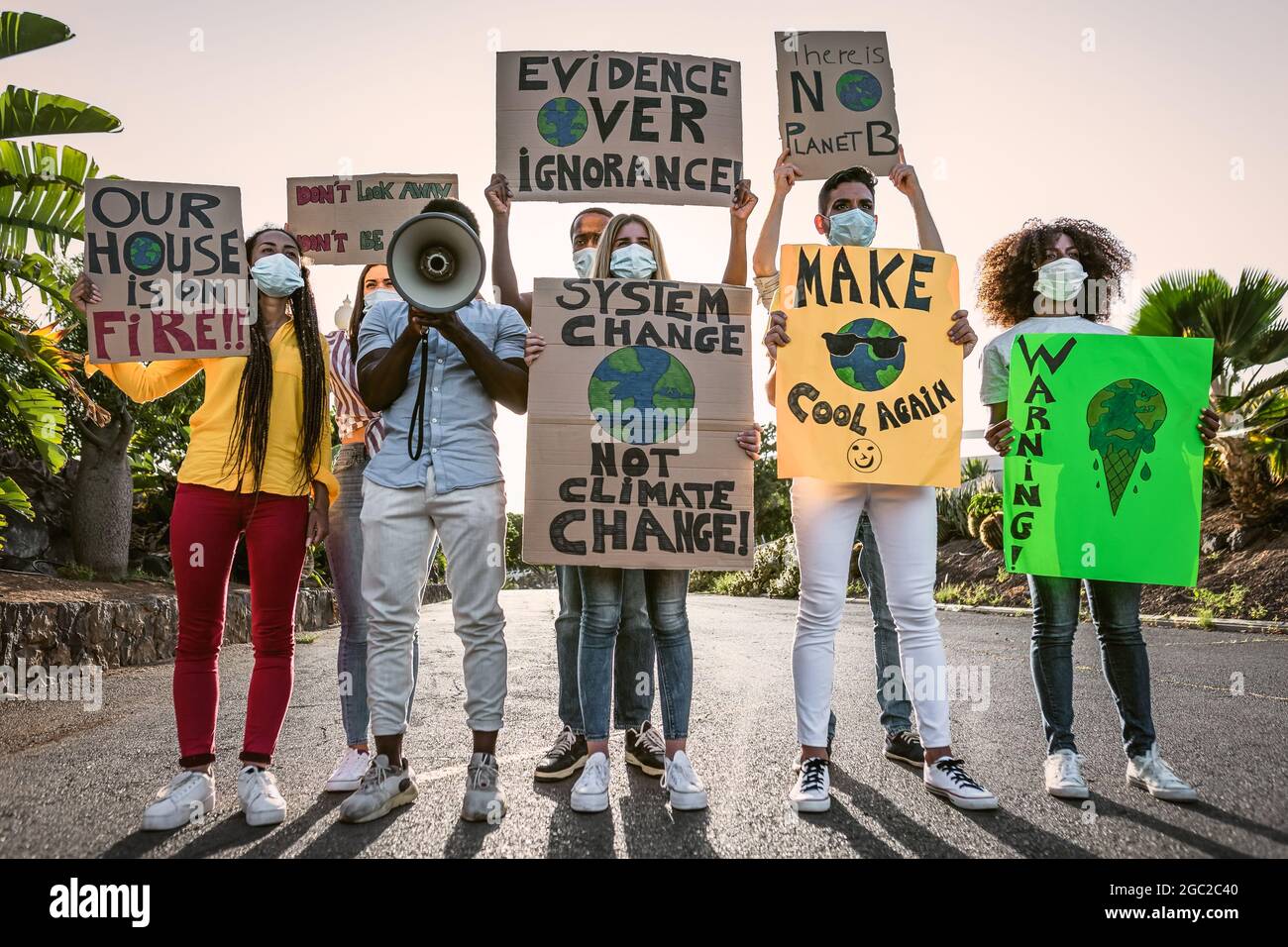 Gruppo di attivisti che protestano per il cambiamento climatico durante il civid19 - persone multirazziali che lottano su strada con bandiere per i disastri ambientali Foto Stock