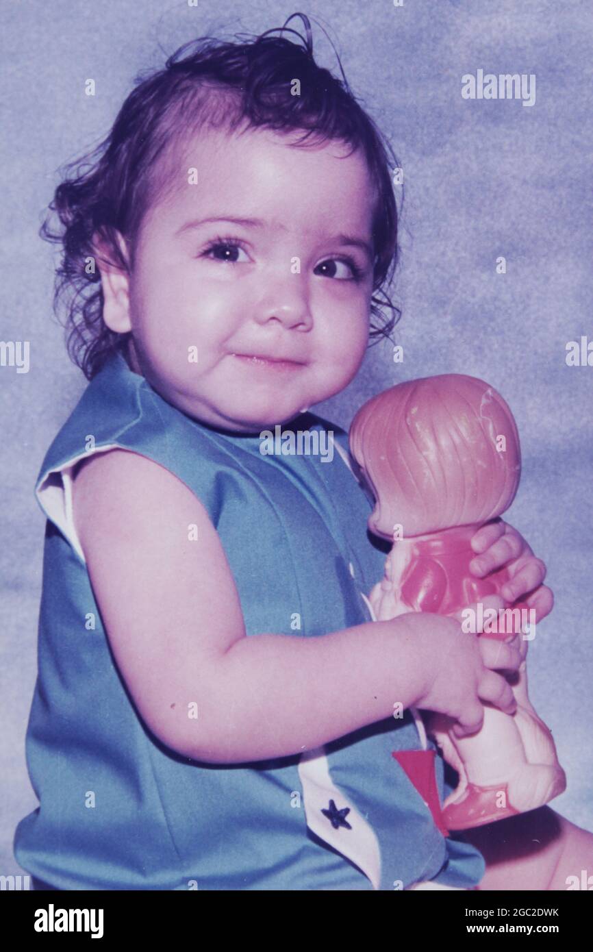 Una vecchia foto di una bambina simpatica e sorridente che stringe la sua  bambola da gioco Foto stock - Alamy