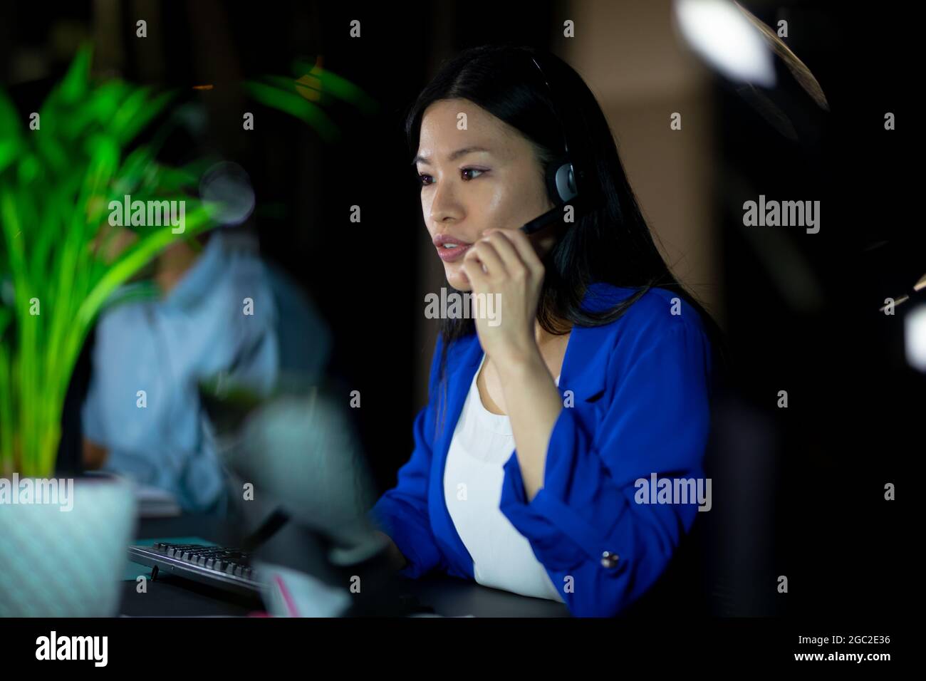 Donna d'affari asiatica che lavora di notte indossando le cuffie Foto Stock