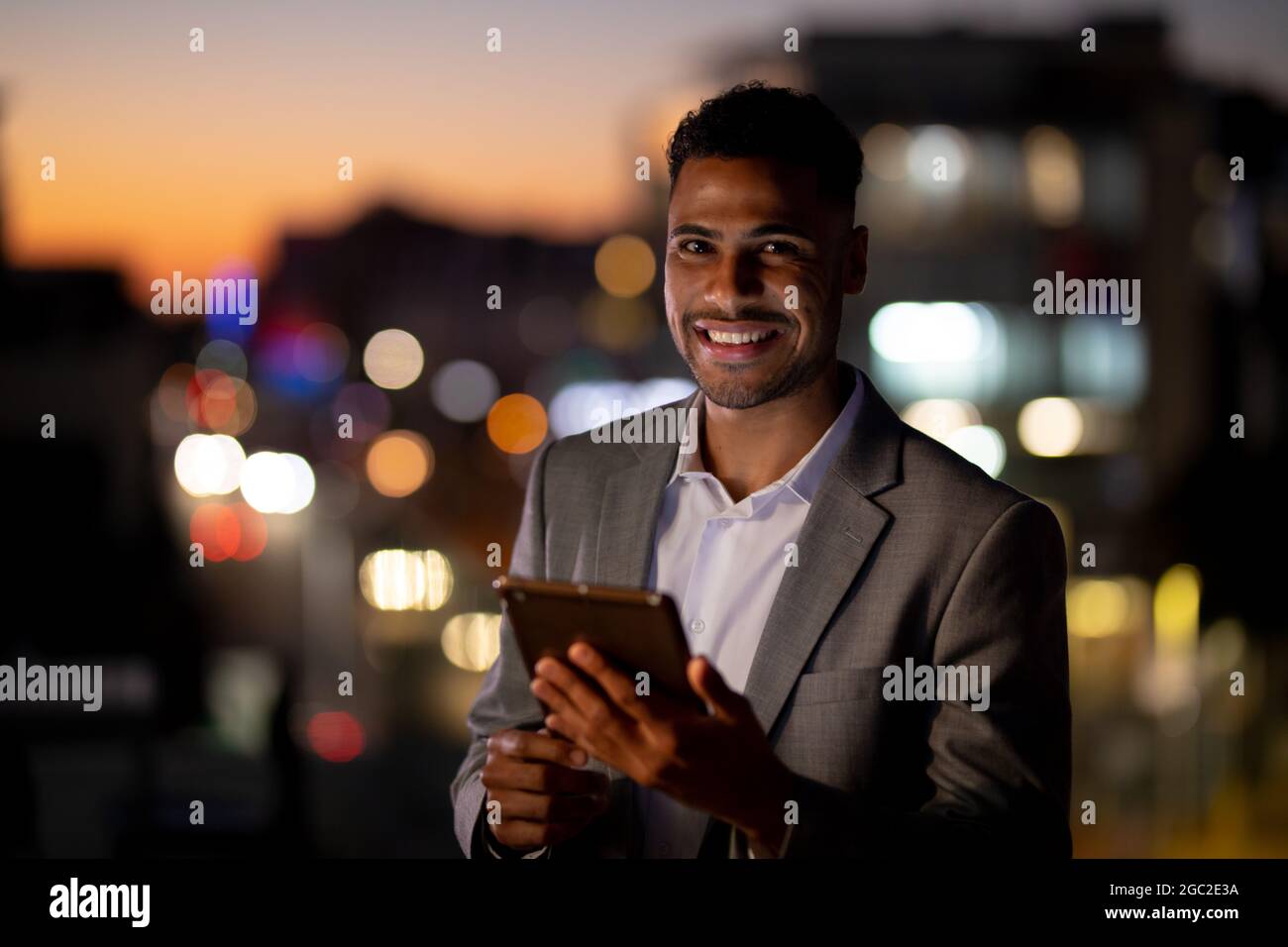 Ritratto di uomo d'affari misto corsa che lavora di notte con tablet Foto Stock