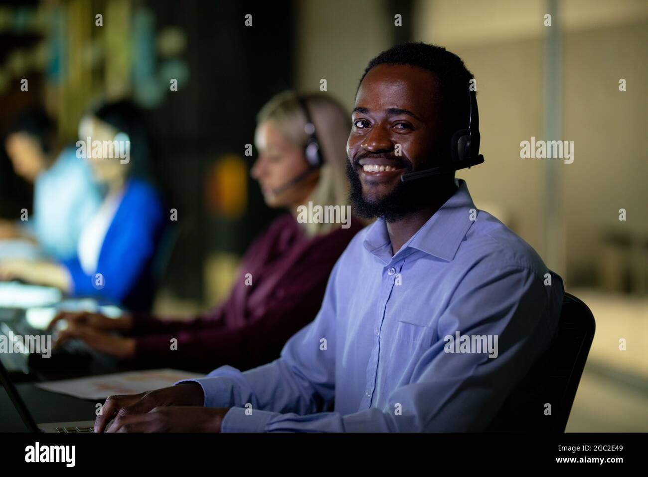 Ritratto di un uomo d'affari afro-americano che lavora di notte indossando la cuffia Foto Stock