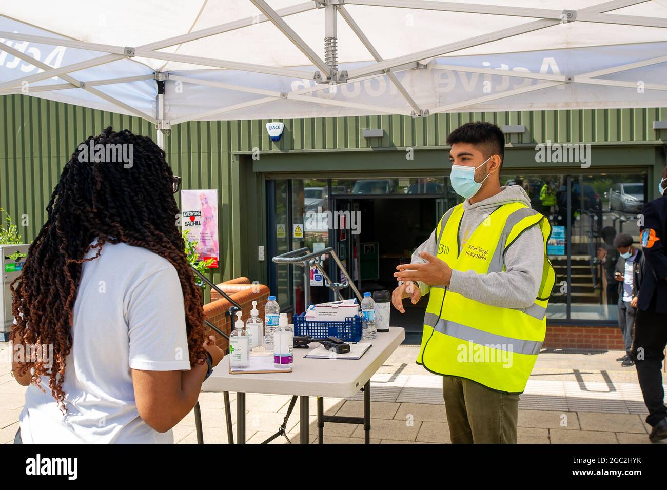 Slough, Berkshire, Regno Unito. 6 agosto 2021. Questa mattina è stata un'intensa mattinata al Salt Hill Activity Center di Slough, mentre la gente del posto è venuta a ricevere la prima o la seconda vaccinazione di Covid-19. Giovani studenti universitari volontari erano a disposizione per aiutare i pazienti e contribuire a rendere il processo senza soluzione di continuità. Credit: Maureen McLean/Alamy Live News Foto Stock