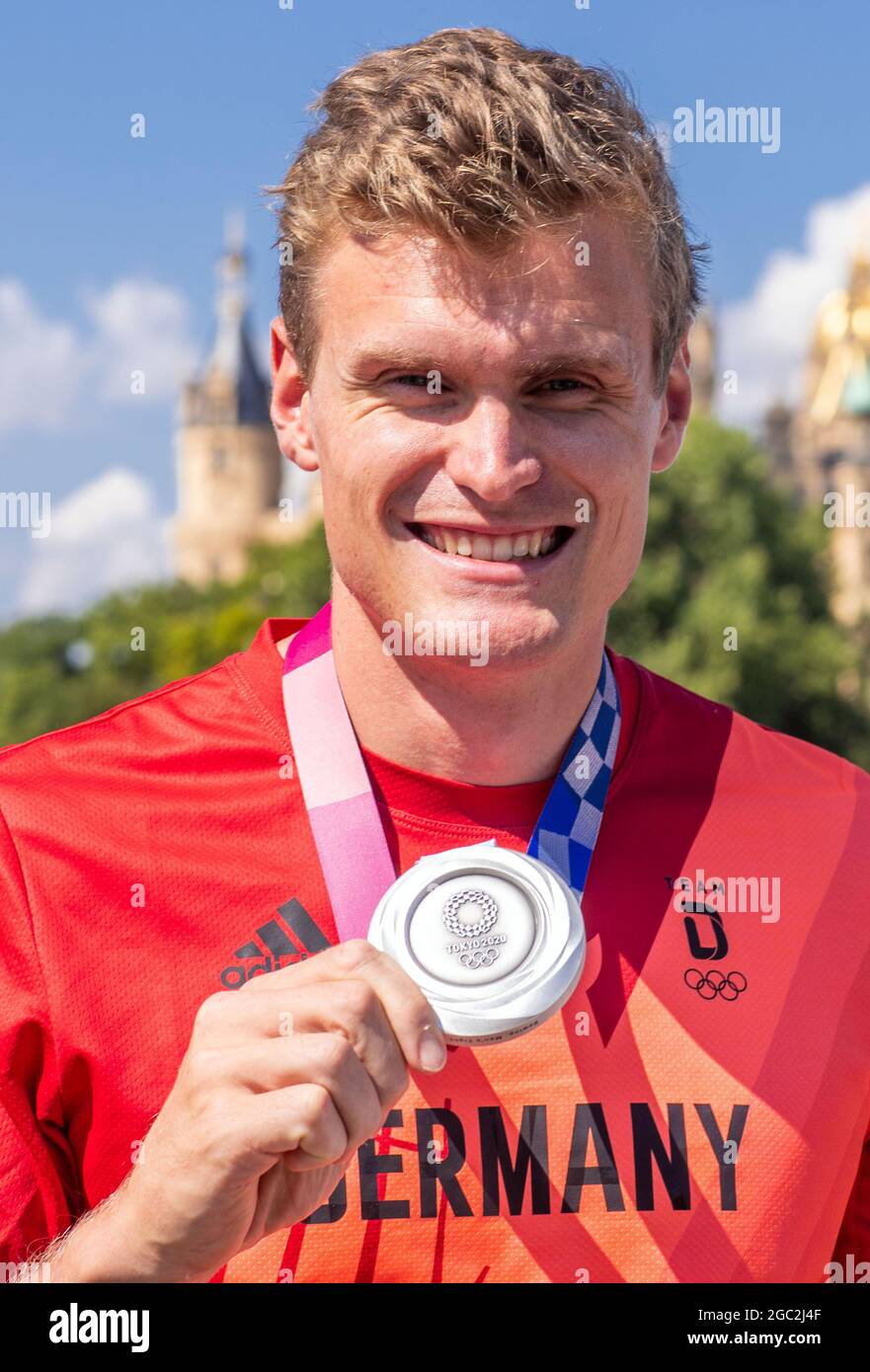 Schwerin, Germania. 06 agosto 2021. Hannes Ocik, colpo in tedesco canottaggio otto ai Giochi Olimpici di Tokyo, si erge con la sua medaglia d'argento alla reception di fronte al Castello di Schwerin. Ocik è stato accolto al club canottaggio Schwerin dopo il suo ritorno dal Giappone. Credit: Jens Büttner/dpa-Zentralbild/dpa/Alamy Live News Foto Stock