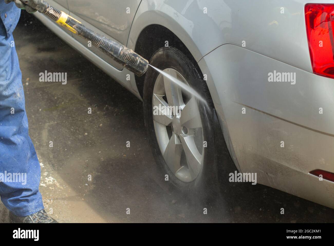 L'auto viene lavata al lavaggio dell'auto. Lavare l'auto dallo sporco. Attrezzature per spruzzare acqua ad alta pressione per lavare le superfici delle auto. Foto Stock