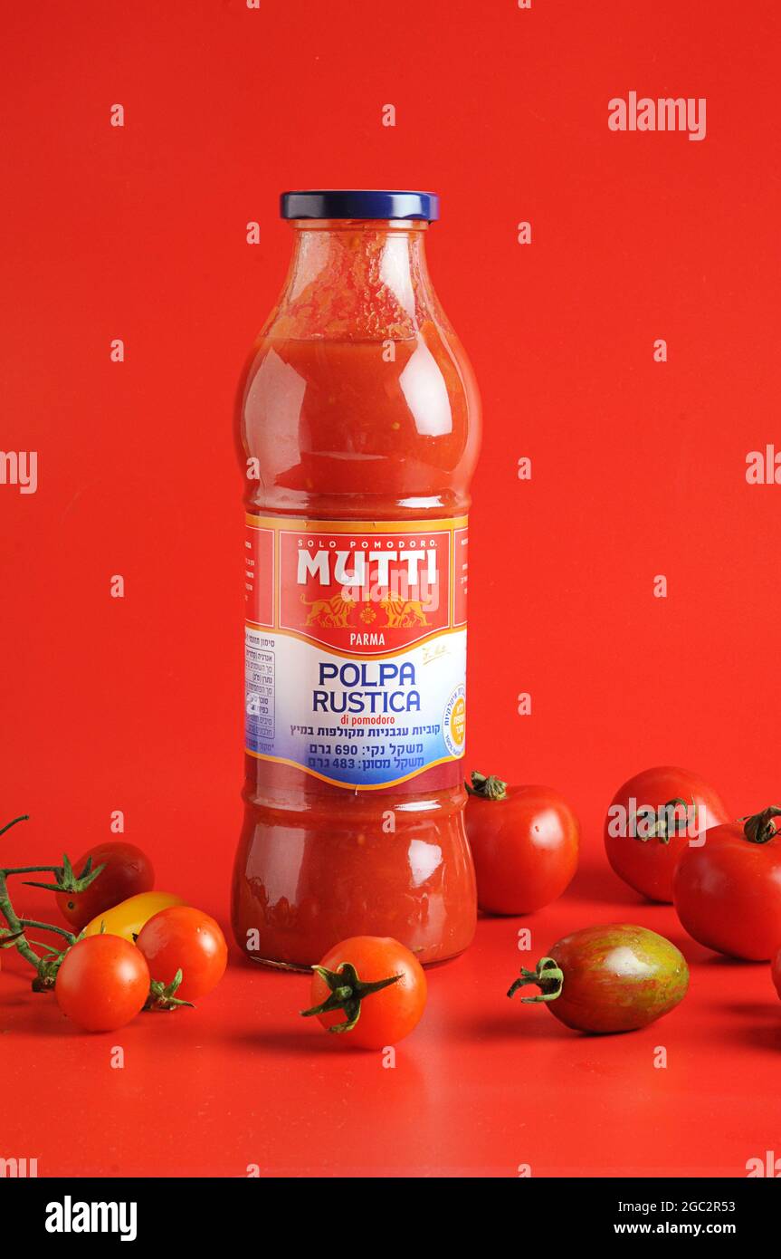 Pomodori maturi freschi su fondo rosso con pomodori pelati Mutti Foto Stock