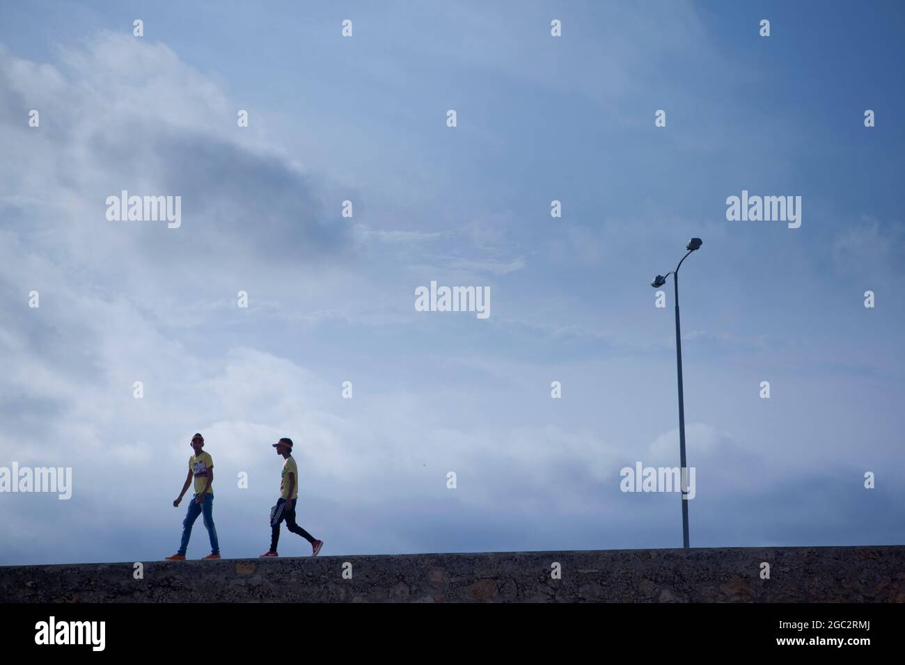 La gente del posto si stacca lungo un muro di mare ai margini della vecchia città fortificata di Cartagena, Colombia. Foto Stock