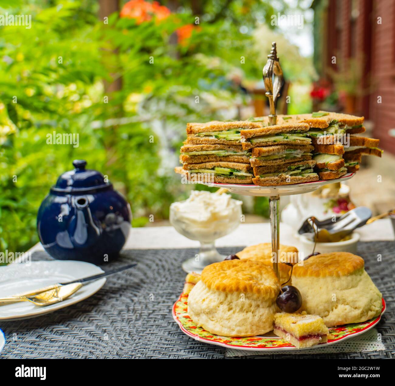 Tradizionale tè inglese panna con scones e cetrioli sandwich in un patio giardino Foto Stock