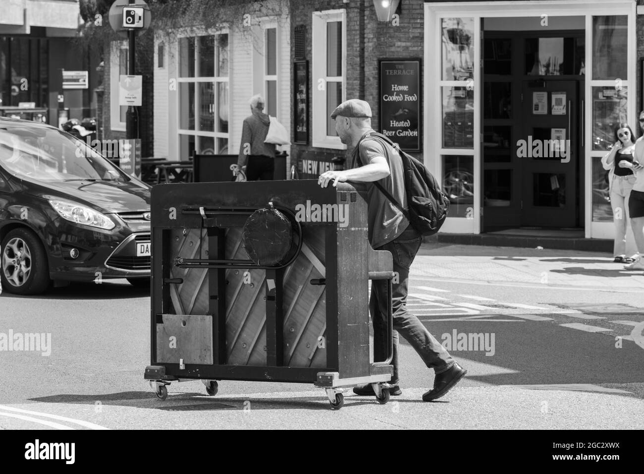 Il centro di York presenta un pianoforte spinto lungo la strada da un artista di strada, York, North Yorkshire, Inghilterra, Regno Unito. Foto Stock