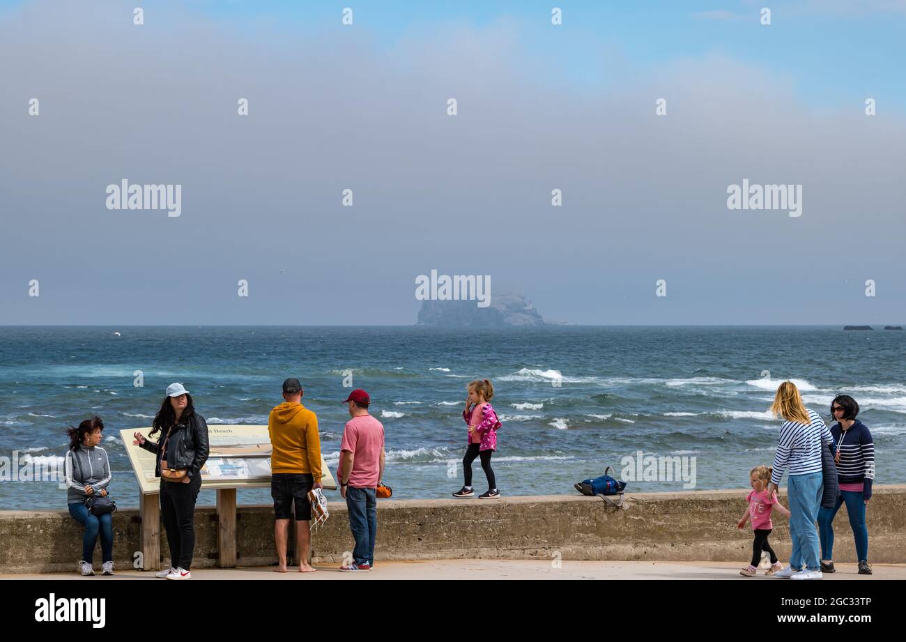 North Berwick, East Lothian, Scozia, Regno Unito, 6 agosto 2021. Regno Unito tempo: misty giorno prima della pioggia pesante: La città è avvolta in nebbia di mare come la gente cammina lungo la passeggiata. Nella foto: Il Bass Rock è quasi invisibile attraverso il Firth of Forth da Milsey Bay Foto Stock