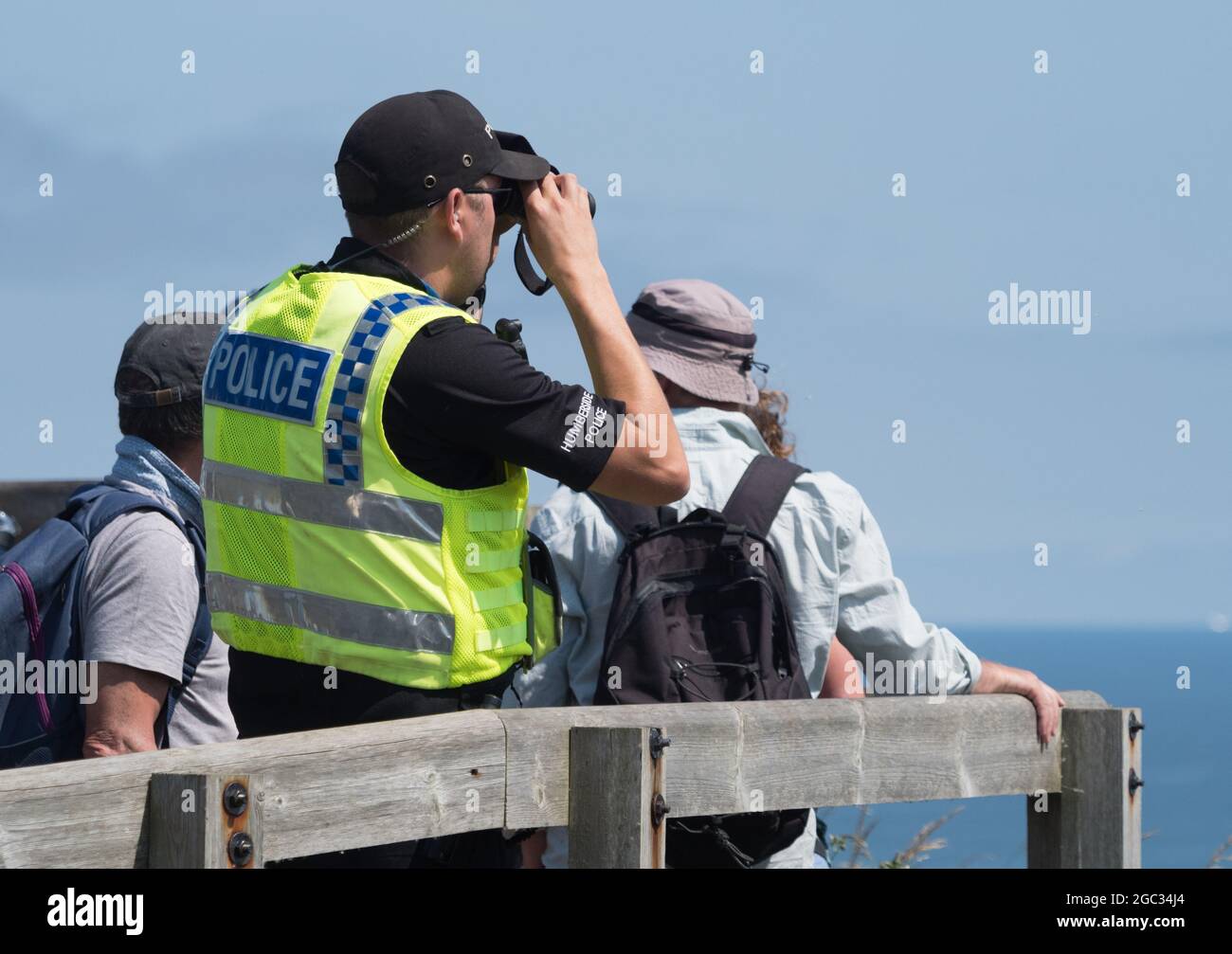 Un ufficiale di polizia maschile guarda fuori da un punto di vista con binocoli Foto Stock