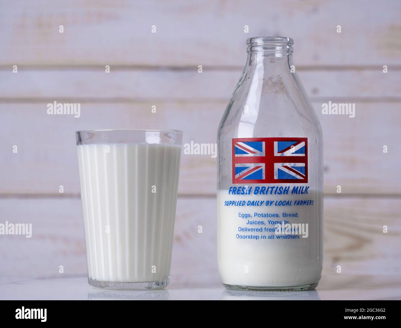 Un bicchiere di latte accanto a un tradizionale biberon di vetro britannico con design Union Jack flag. Foto Stock