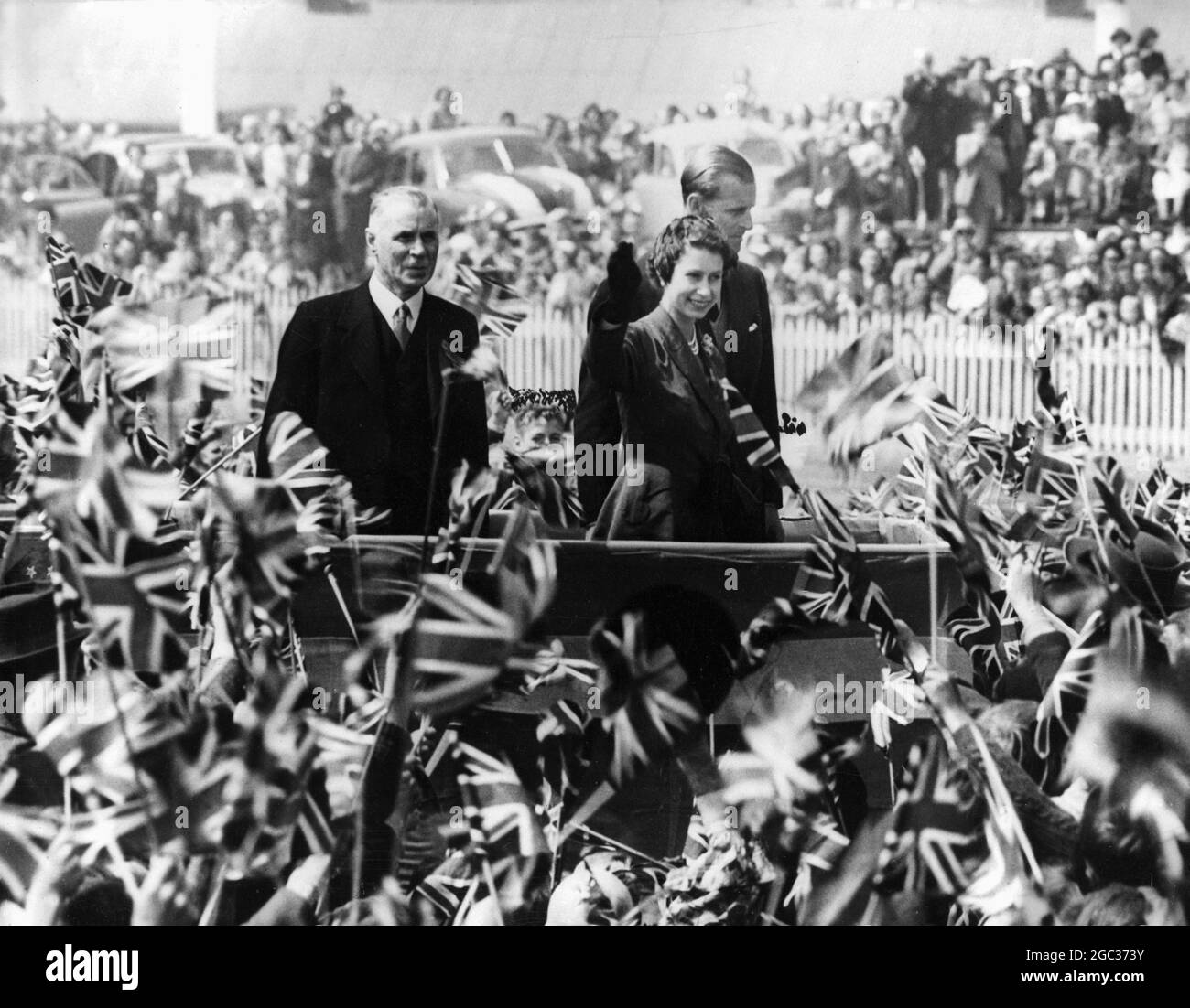 Il Royal Tour la Regina e il Duca circondati da una massa di bambini che sventolano bandiere quando hanno partecipato ad un picnic per bambini al circuito di Forbury Park, Dunedin, durante le fasi di chiusura del loro tour della Nuova Zelanda. 1 febbraio 1954 Foto Stock