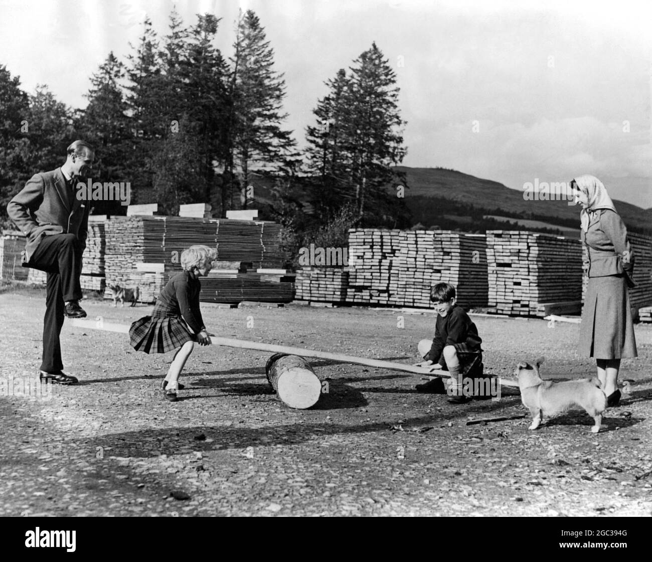 Il divertimento per le vacanze in visita ha visto il principe Carlo e la principessa Anna in un luogo visto come il duca di Edimburgo e la regina guardare sopra. Sono ad una segheria sulla tenuta Balmoral. Dopo che avevano visto i tronchi che erano stati segati, i bambini hanno chiesto una sega vedere. Il duca organizzò una tavola sopra il tronco e il principe e la principessa ebbero la loro giocata. 15 settembre 1957 Foto Stock