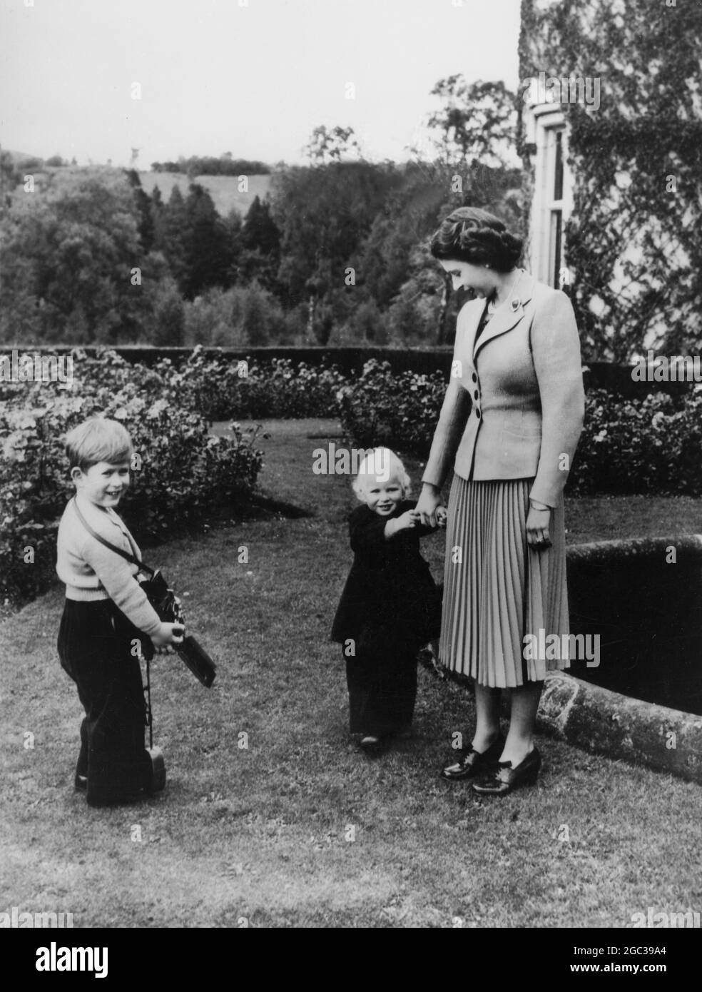 Balmoral: Il principe Carlo sorride felicemente mentre attende di scattare una foto della regina e della principessa Anna nei motivi di Balmoral 29 aprile 1953 Foto Stock