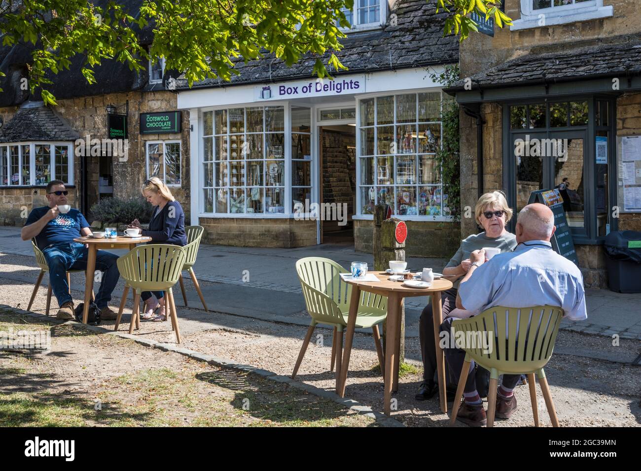 La gente gode del sole primaverile, fuori da una sala da tè nella città di Cotswold di Broadway nel Worcestershire. Foto Stock